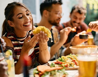 Woman smiling while eating lunch with friends at restaurant