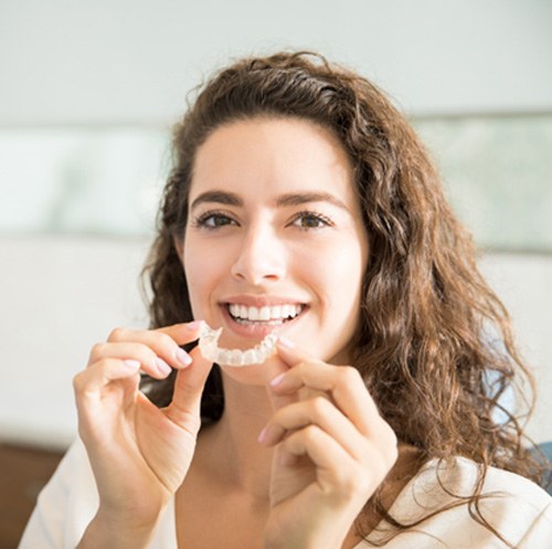 Smiling woman holding clear aligner