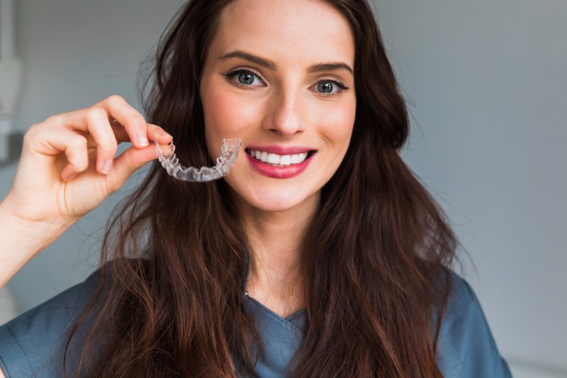 A beautiful smiling woman holding an Invisalign tray