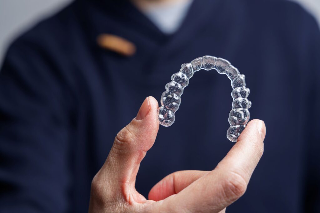 Man in blue scrubs holding Invisalign tray